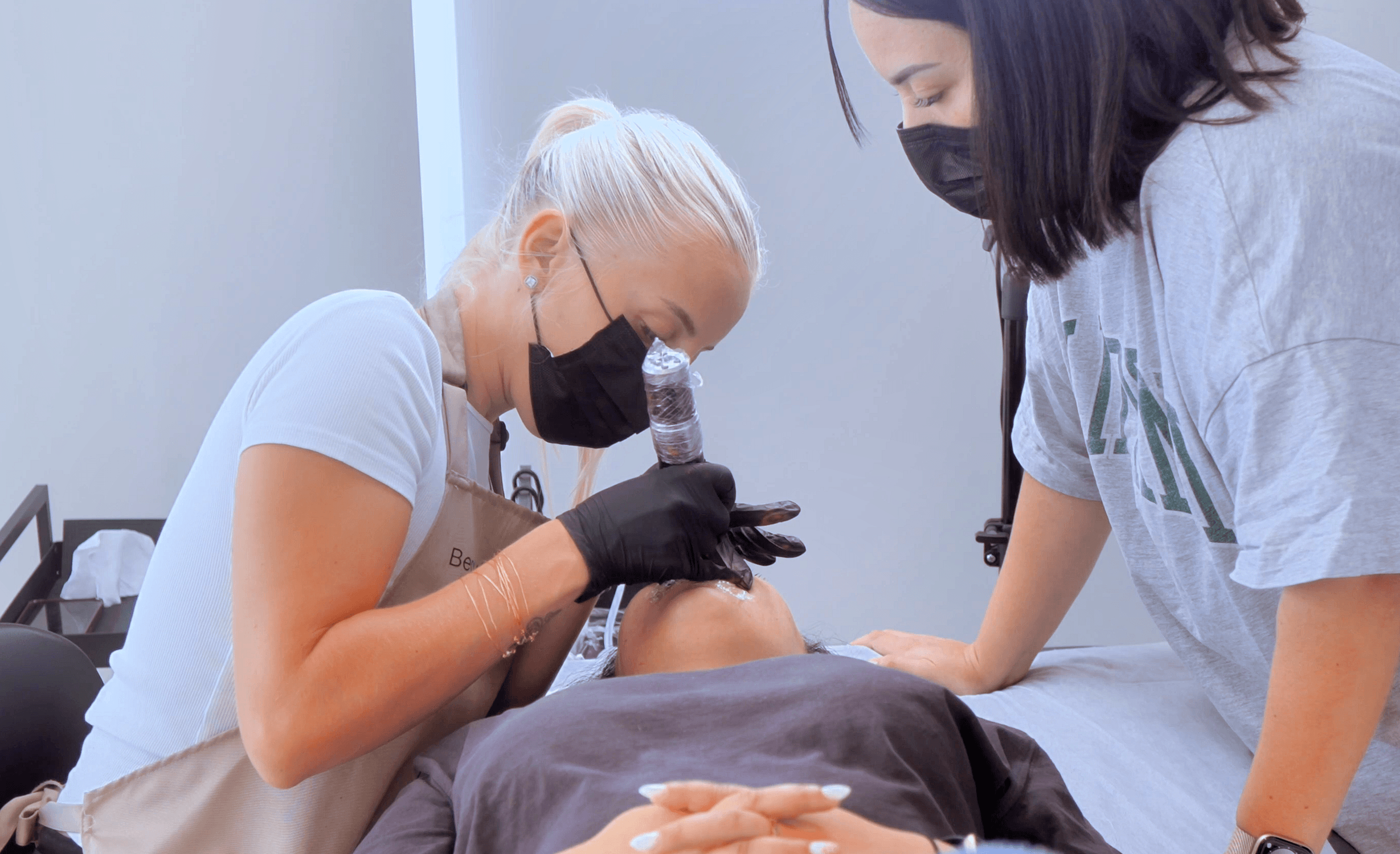 Élève en formation présentielle de tatouage des lèvres permanent Candy Lips pratiquant la pigmentation sous l'œil de la formatrice Habiba Med.